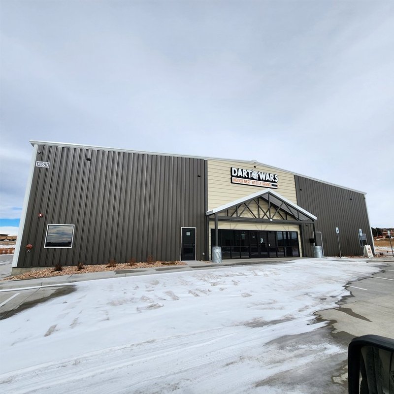 Completed Dart Wars indoor arena exterior, a metal building with a gabled entry canopy