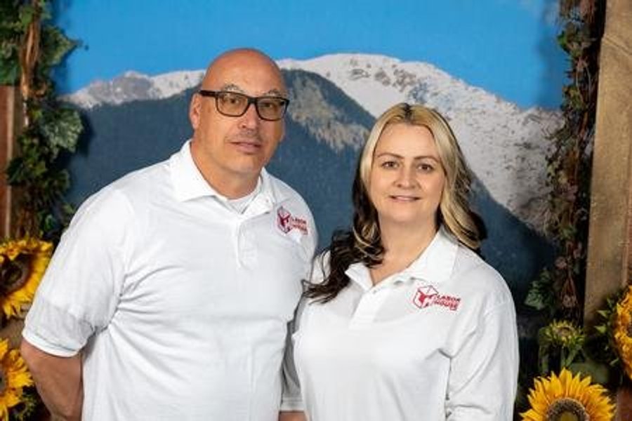 Curtis Byers II and Annie Fodge, owners of Labor House, in branded polo shirts against a Colorado mountain backdrop