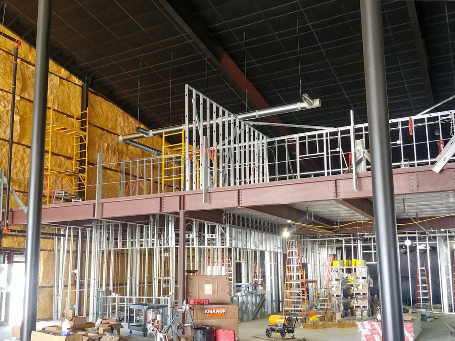 Mezzanine steel framing with batt insulation and ductwork on an active jobsite