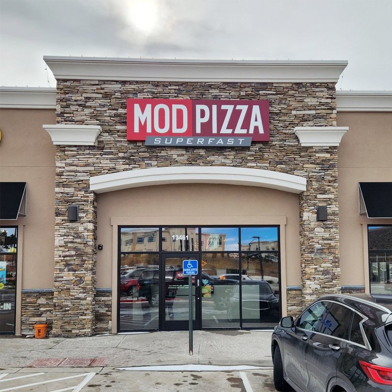Completed MOD Pizza storefront with stacked stone facade and glass entry doors