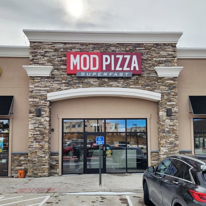 Completed MOD Pizza storefront with stacked stone facade and glass entry doors