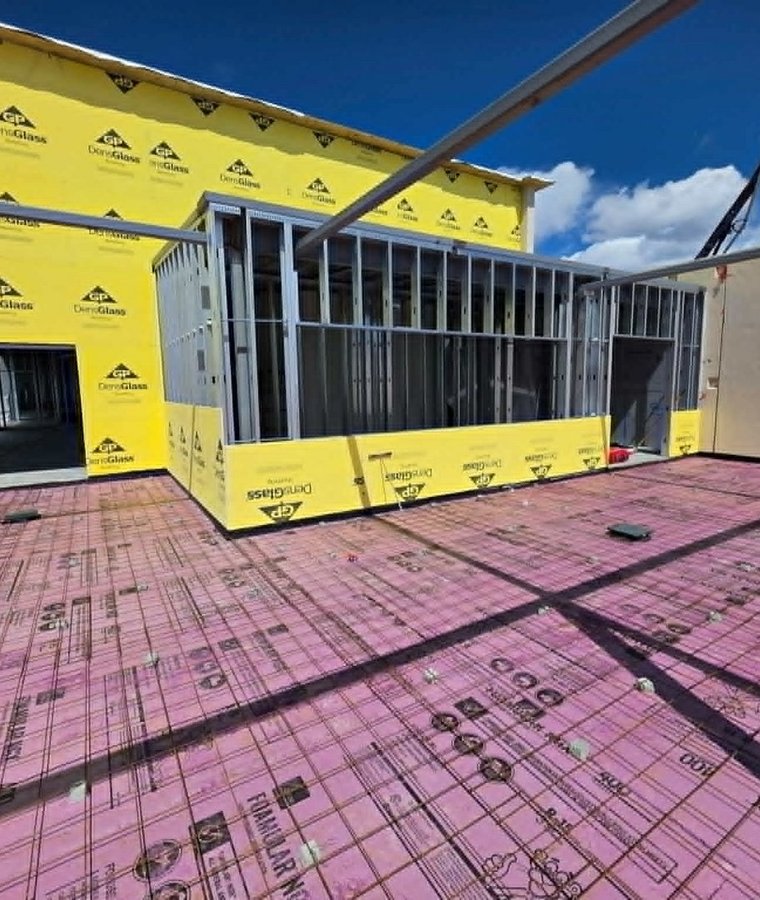 Rooftop metal stud framing with yellow DensGlass sheathing and rigid insulation board on a Labor House job
